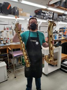 David standing, holding a baritone saxophone body and bell