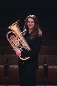 Eli in a suit holding a euphonium