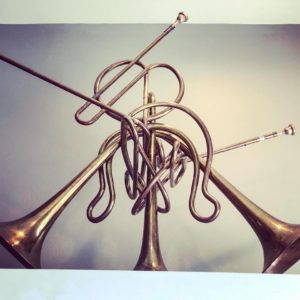 A tangled, playable sculpture made from brass instrument tubes